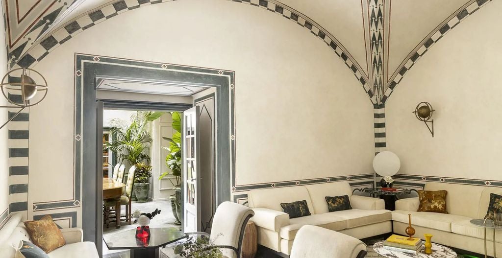 Elegant boutique hotel in Florence with beige stone facade, arched windows, ornate balconies, and classic Italian architecture on tree-lined street