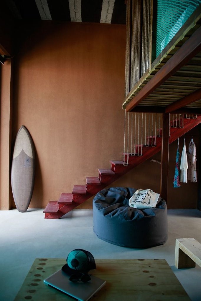 Minimalist coastal bedroom with white linens, wooden accents, and panoramic ocean view at luxurious surf-inspired accommodation in scenic Portugal.