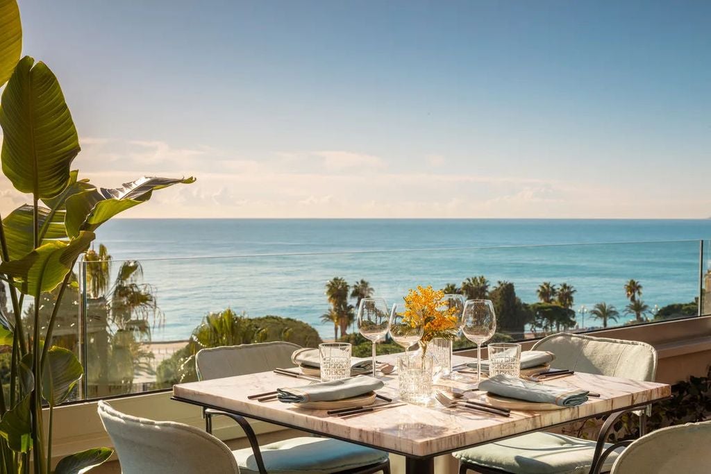 Elegant 5-star hotel facade with Belle Époque architecture, wrought iron balconies, and ornate stonework overlooking Nice's Mediterranean coast