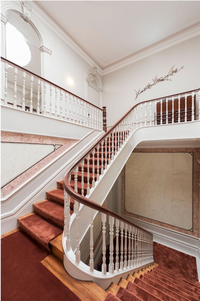 Elegant historic townhouse with classic Portuguese facade, wrought iron balconies, and manicured garden entrance in soft evening light