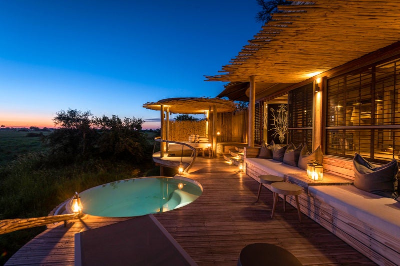 Elevated luxury safari tent overlooking Okavango Delta, with private wooden deck, plunge pool and sweeping savanna views at sunset