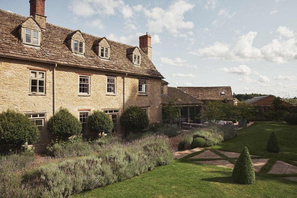 Elegant farmhouse-style hotel room with rustic wooden furniture, crisp white linens, and soft green thyme-inspired accents in a serene UK countryside setting