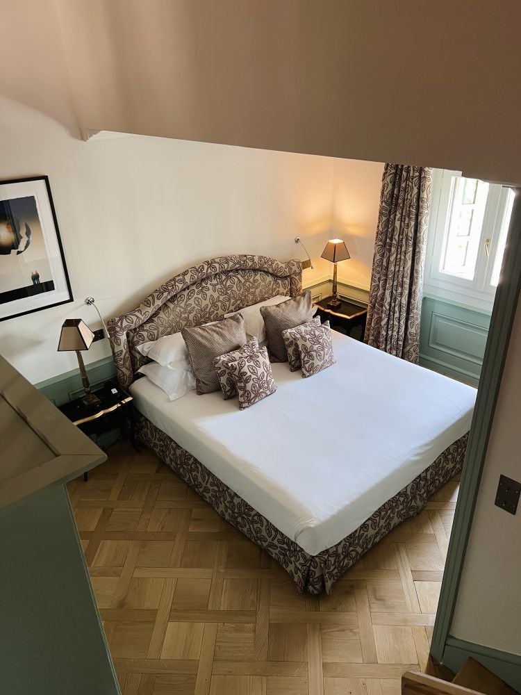 Luxurious duplex hotel room at Hotel Le Saint in France with elegant decor, plush bedding, and expansive windows overlooking a scenic cityscape.