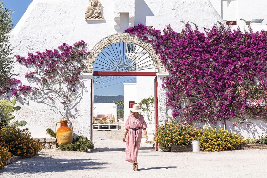 Historic stone masseria hotel with whitewashed walls, rustic archways and Mediterranean landscaping nestled among olive groves in Puglia