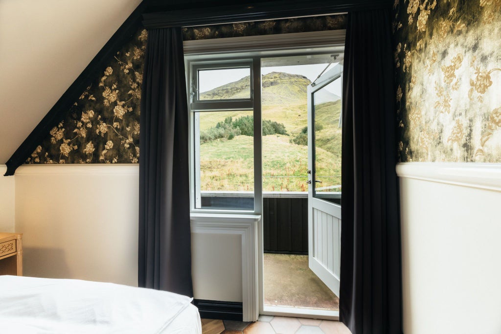 Cozy single room at Skálakot Manor Hotel with plush white bedding, wooden floors, minimalist Icelandic design, and soft natural lighting.