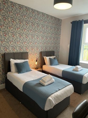 Charming rustic bedroom at historic Wheatsheaf Inn with soft neutral linens, exposed wooden beams, and elegant traditional British countryside decor