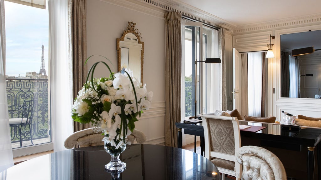 Elegant Parisian luxury suite with panoramic city views, plush ivory furnishings, and dramatic Eiffel Tower glimpse through expansive floor-to-ceiling windows