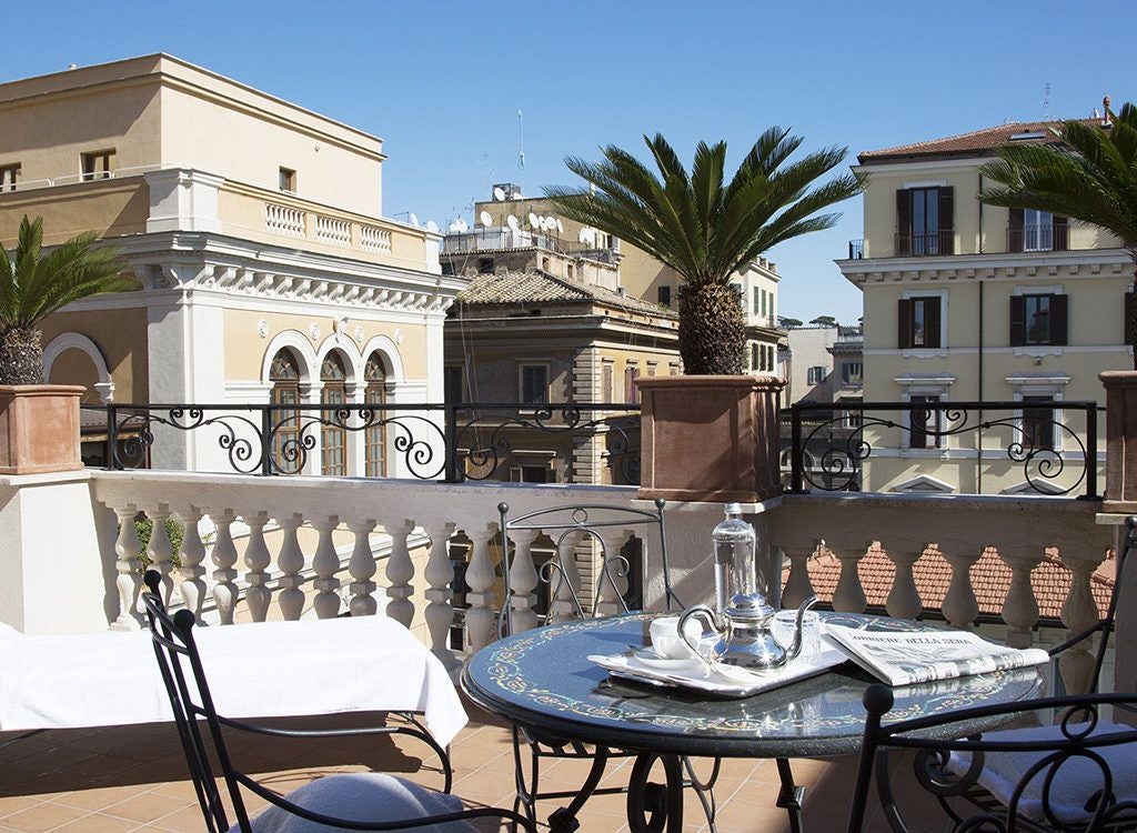 Elegant marble-clad luxury suite with panoramic windows, plush white furnishings, and sophisticated Italian design in a prestigious Roman hotel.