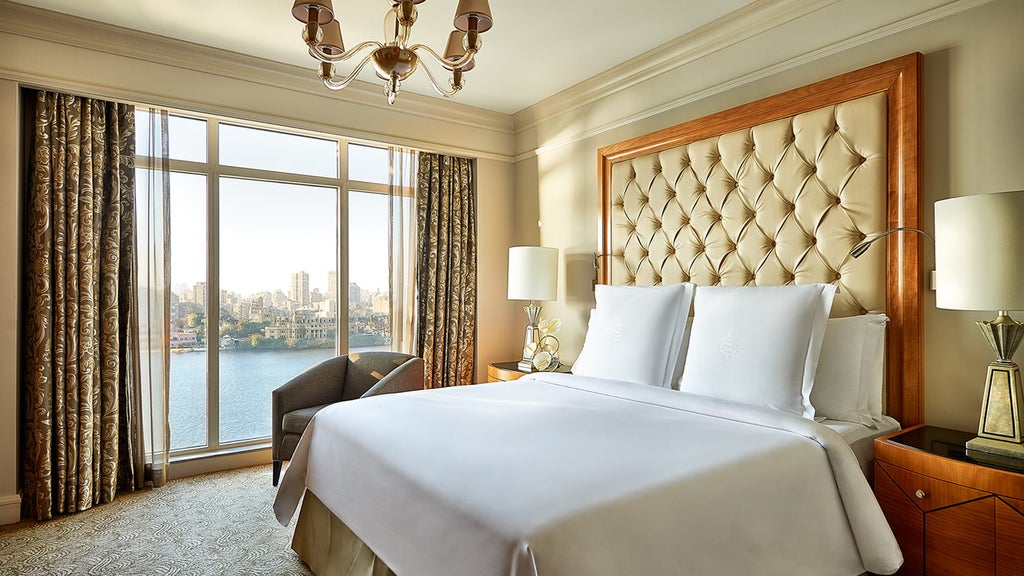 Opulent riverside hotel with grand archways and palm trees reflecting in the Nile, illuminated by warm golden lighting at dusk