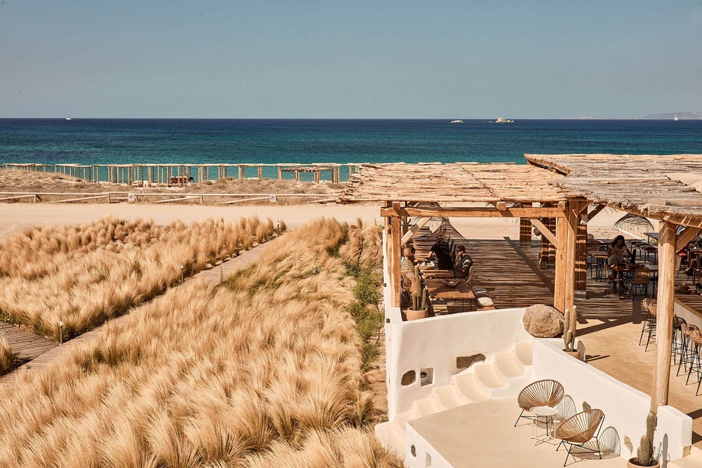 Luxurious white-washed Greek hotel nestled on a pristine sandy beach with azure Aegean waters, featuring minimalist architecture and elegant pool area