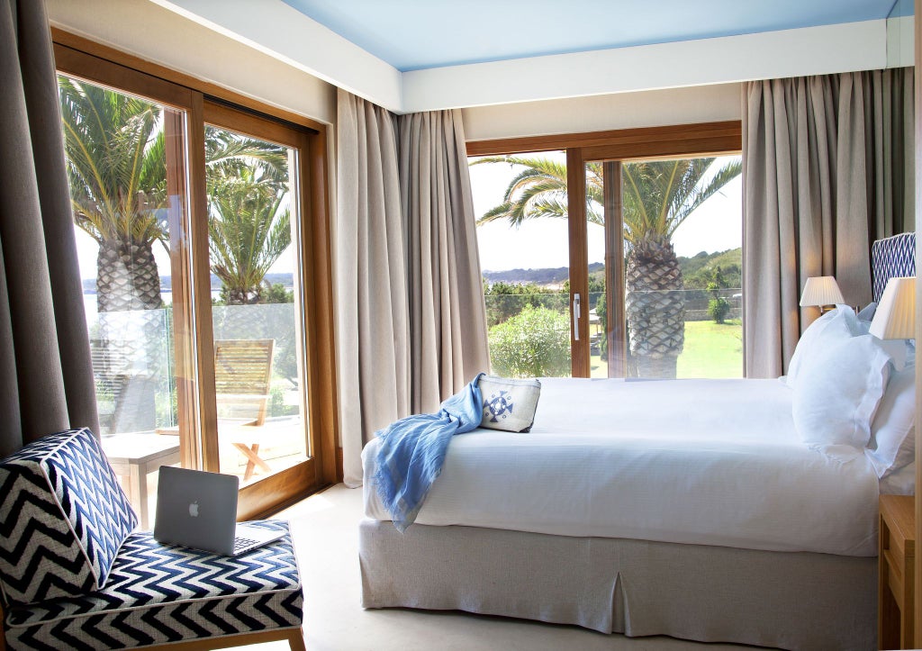 Luxurious beachfront hotel room with minimalist design, warm sunset lighting, ocean view, and modern white furnishings at Gecko Beach Club in coastal Spain.