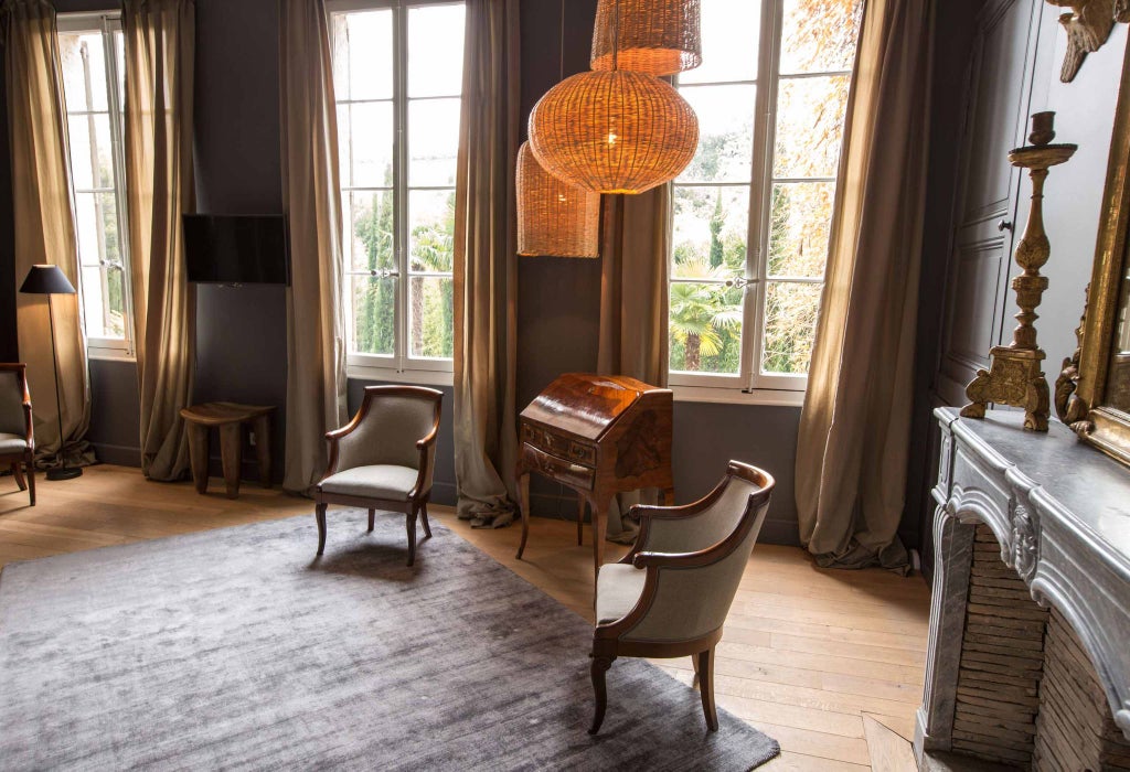 Elegant Naples Suite at La Divine Comédie, featuring ornate French decor, plush white bedding, and soft natural lighting in a sophisticated bedroom setting