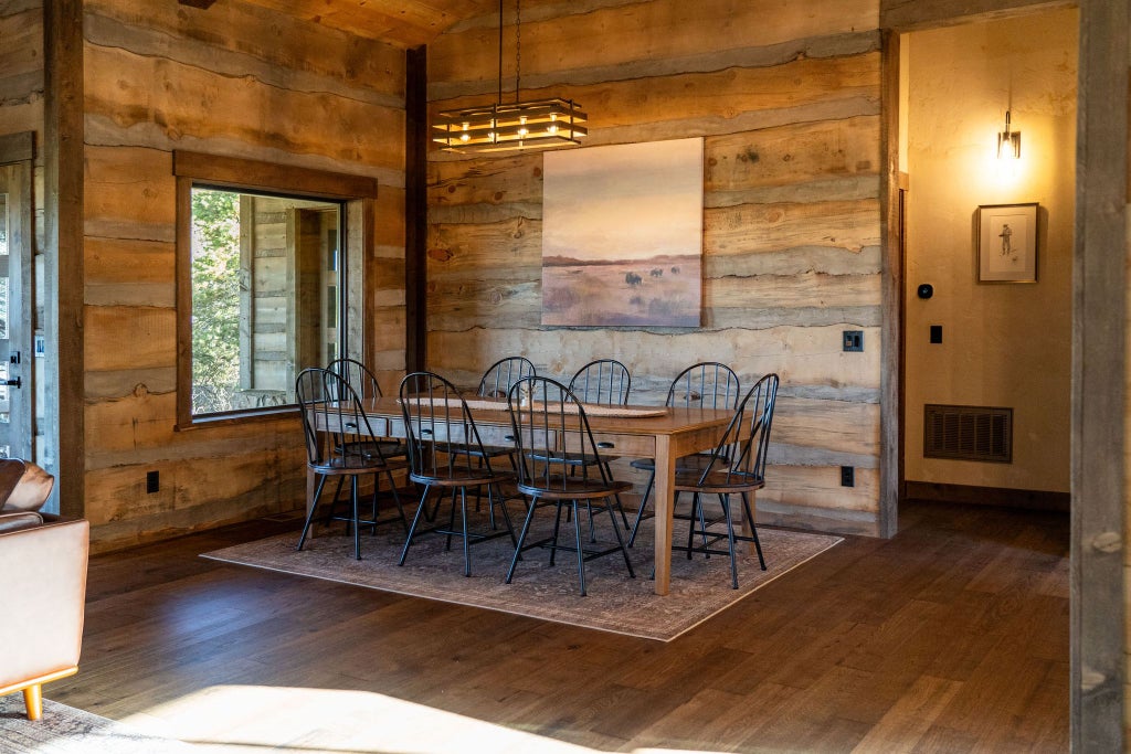 Rustic wood-paneled lodge room with plush king bed, scenic mountain view windows, and warm earth-toned textiles at mountain retreat near National Park