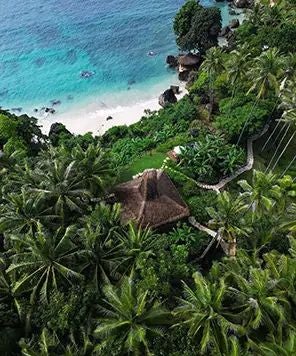 Luxurious seaside resort with traditional thatched-roof villas overlooking crystal blue waters of Sumba, Indonesia, with lush tropical landscape