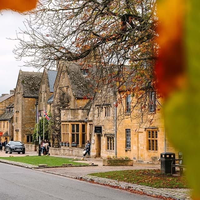 Historic luxury hotel with Tudor-style architecture, stone facade, manicured gardens, and elegant archways in the Cotswolds countryside of United Kingdom.