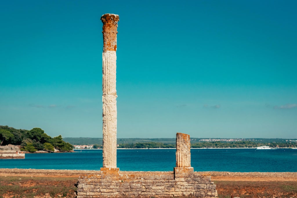 Scenic coastal view of historic Brijuni islands featuring ancient Roman ruins, crystal-blue Adriatic waters, and luxury yachts in harbor