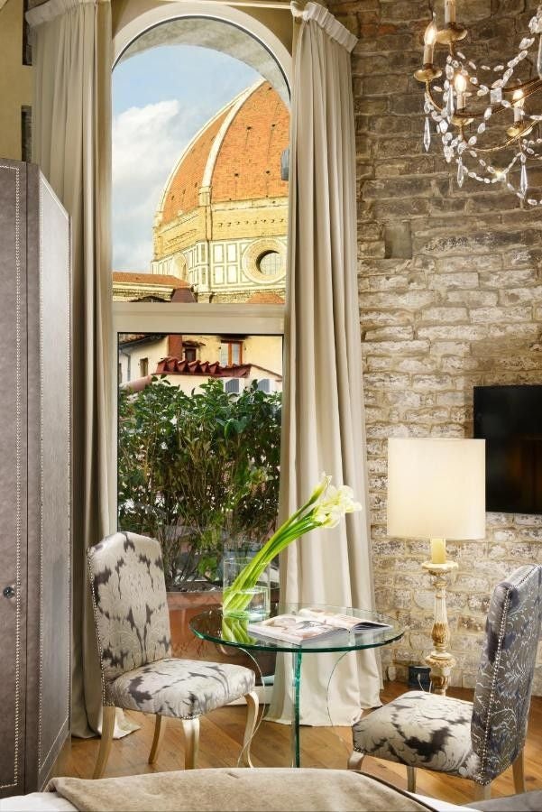 Elegant Italian hotel with medieval stone architecture, golden evening lighting illuminating arched windows and ornate facade details