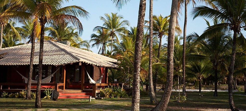 Luxurious wooden bangalow suite with elegant interior, tropical Brazilian decor, and serene view of lush green landscape at Fazenda São Francisco do Corumbau