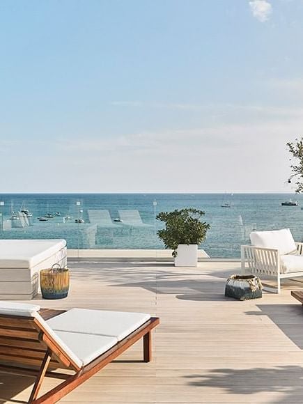 Luxurious rooftop junior suite at Nobu Hotel in Ibiza Bay, Spain, with modern white decor, elegant furnishings, and panoramic coastal views.