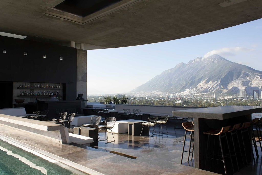 Modern glass-fronted boutique hotel with minimalist design, sleek white exterior, and urban architectural lines against a bright sky in Monterrey, Mexico