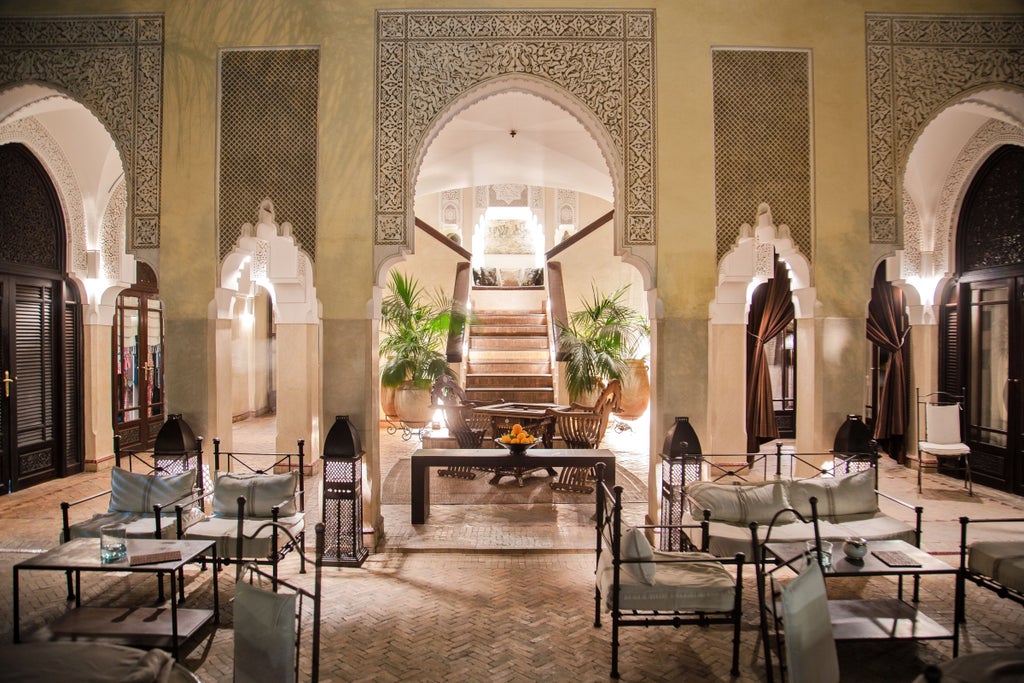 Elegant Moroccan riad courtyard with central fountain, palm trees and traditional archways, surrounded by terracotta walls and balconies