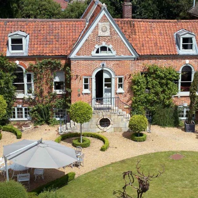 Elegant boutique hotel facade with traditional British architecture, warm stone exterior, and charming window details in a picturesque countryside setting