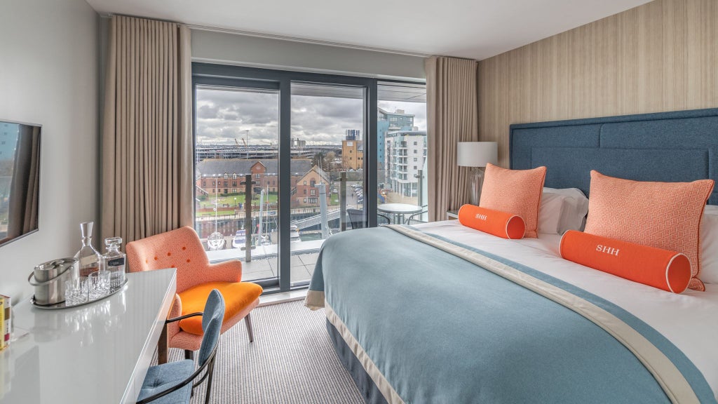 Elegant cosy double hotel room with soft neutral tones, plush bedding, and a charming Juliet balcony overlooking Southampton's scenic harbour view