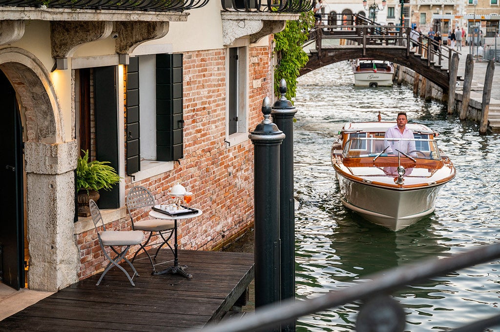 Elegant Venetian boutique hotel with ornate baroque interiors, overlooking Santa Maria della Salute basilica against canal ba