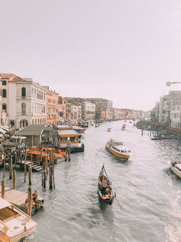 Ornate Renaissance buildings along Venice's Grand Canal at sunset, reflecting golden light on the rippling blue water below