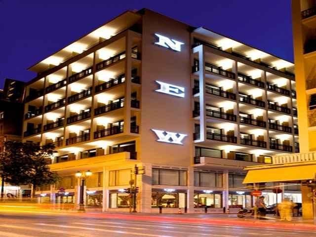 Contemporary luxury hotel facade in Athens with geometric metal screens, angular white architecture and warm evening lighting