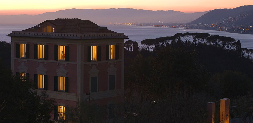 Elegant coastal Italian villa with lush rosemary gardens, terracotta tiles, and panoramic Mediterranean view at golden hour sunset