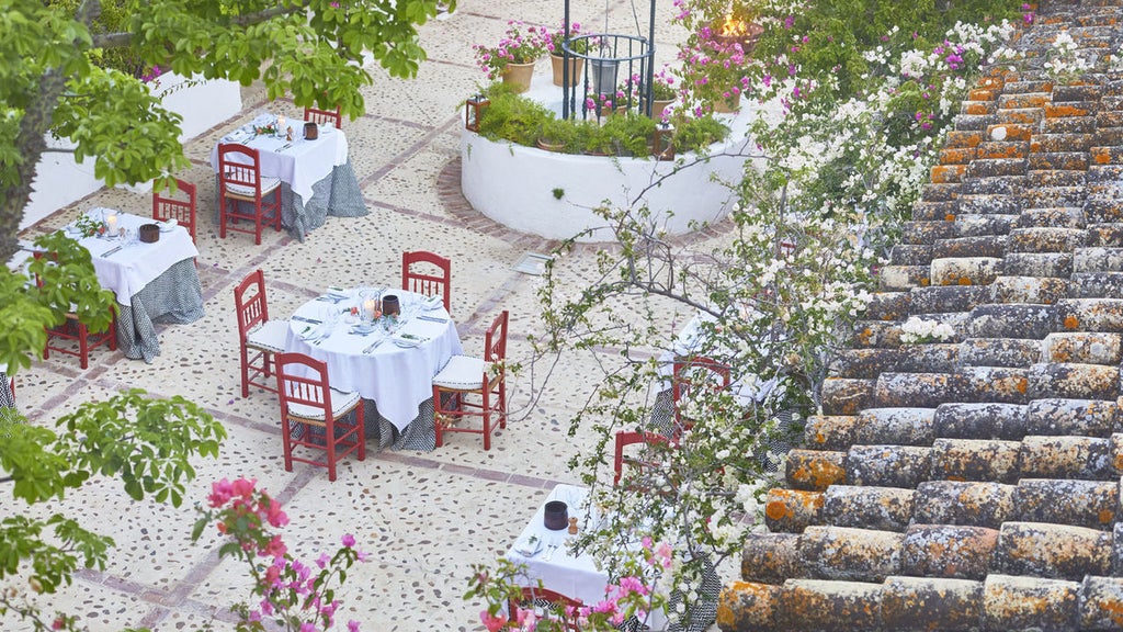 Spanish luxury boutique hotel with whitewashed walls, terracotta roof, and vibrant bougainvillea surrounding an elegant courtyard pool