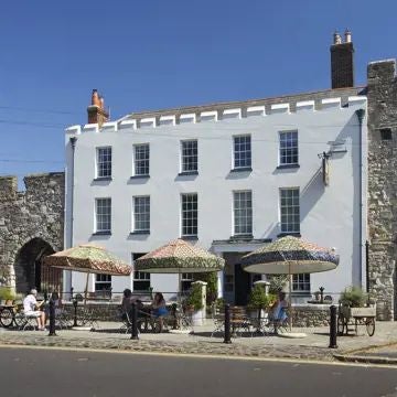 Luxurious stone hotel facade with rustic charm, nestled within historic wall, showcasing elegant windows and warm lighting in scenic United Kingdom setting