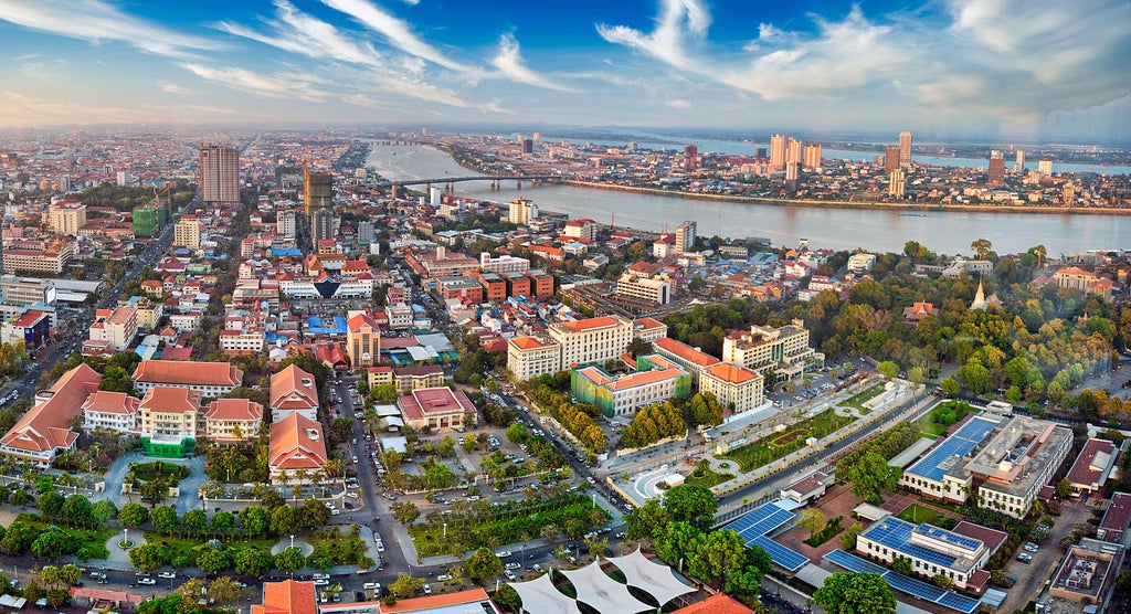 Elegant sunset over Phnom Penh's Royal Palace, with golden spires gleaming and traditional Cambodian architecture silhouetted against vibrant orange sky