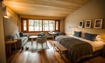 Spacious Peruvian suite with rustic wooden furnishings, panoramic mountain views, and elegant Andean-inspired decor in warm earth tones at Explora Sacred Valley