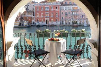 Elegant Venetian palazzo with ornate Renaissance facade, luxurious canal-side terrace, and intricate marble details overlooking historic waterway at dusk