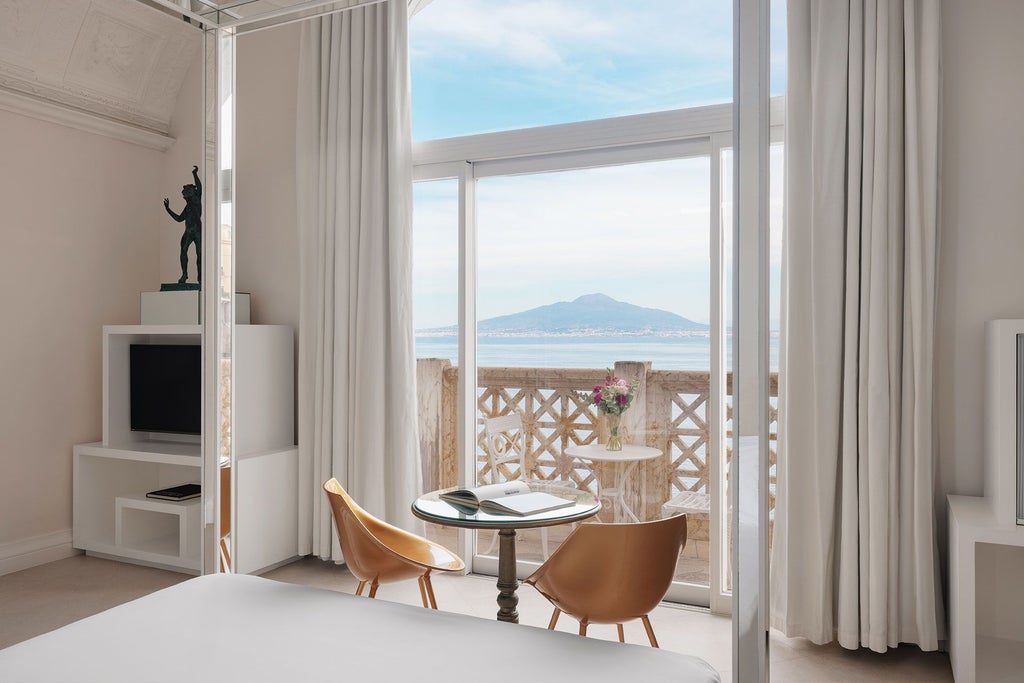 Luxurious seafront suite with elegant white decor, ornate marble bathroom, panoramic Mediterranean views, and classic Italian coastal design elements