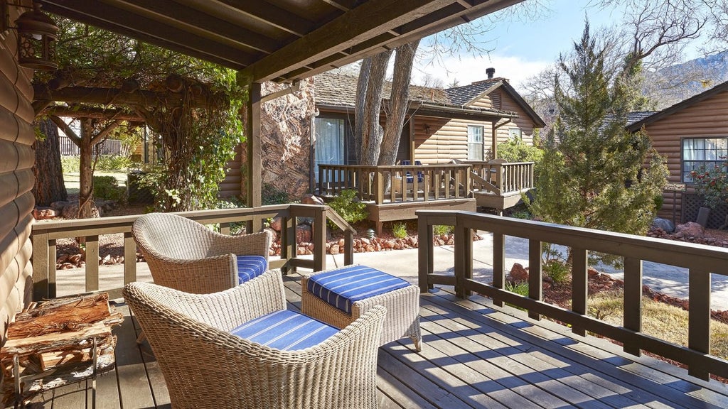 Historic, luxury two-story resort nestled among trees with rustic stone facade, expansive balconies, and elegant archway entrance