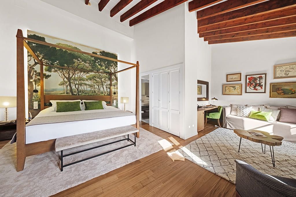 Elegant double room with garden view at L'Avenida Sóller, featuring plush white bedding, modern decor, and lush greenery through large windows in Mallorca, Spain