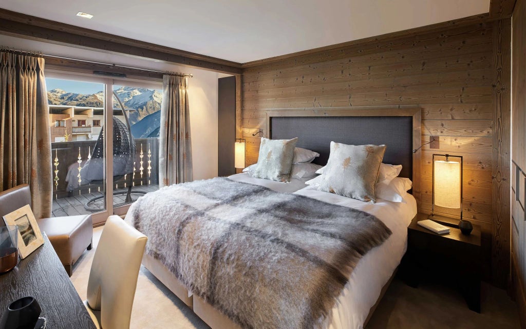 Luxurious two-bedroom alpine apartment with floor-to-ceiling windows, showcasing panoramic mountain scenery and elegant contemporary mountain resort design