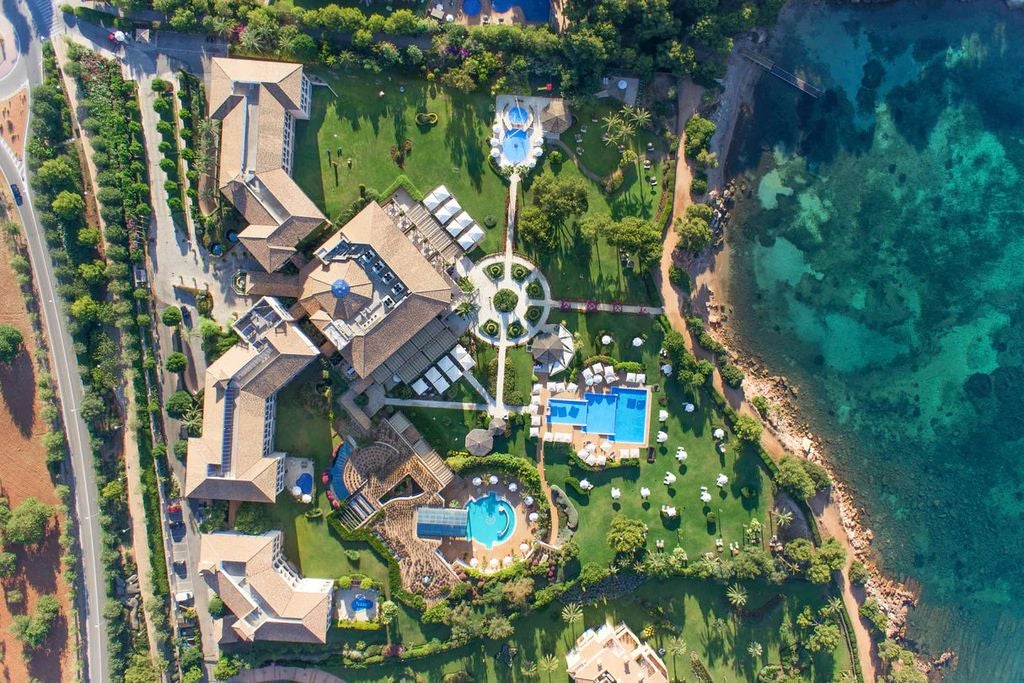 Elegant Mediterranean resort with white stone facade, tropical gardens, fountains and sea-view infinity pools overlooking Mallorca coast