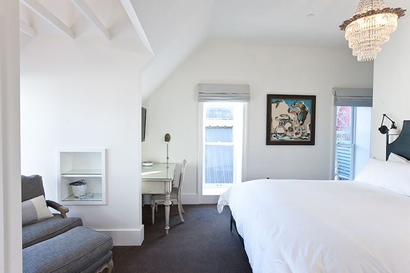 Elegant town king room with historic school architecture, plush white bedding, and minimalist design in a boutique United States hotel setting