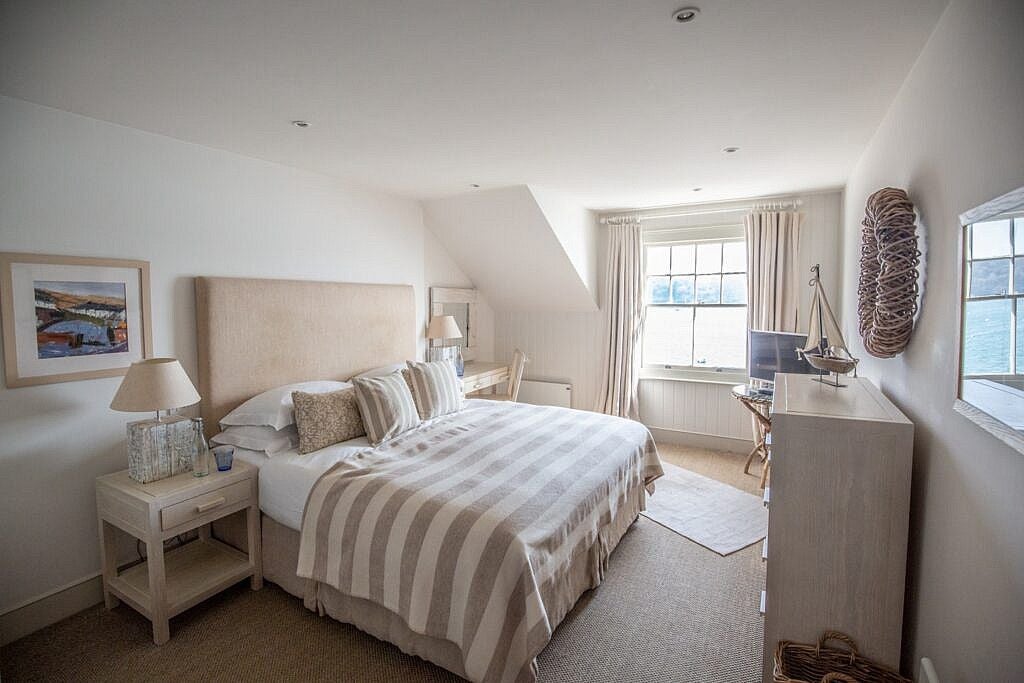 Luxurious superior seaview room at a coastal UK hotel, featuring elegant maritime decor, crisp white linens, and expansive ocean panorama through large windows.