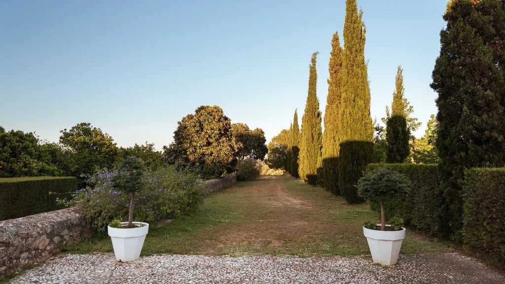 Elegant stone country house with terracotta roof, surrounded by lush green gardens and rolling hills of scenic Portuguese landscape at sunset.