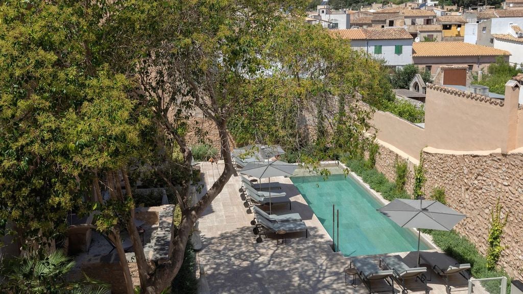 Contemporary Mediterranean villa with infinity pool overlooking mountain ranges, featuring white stone walls and sunlit terrace