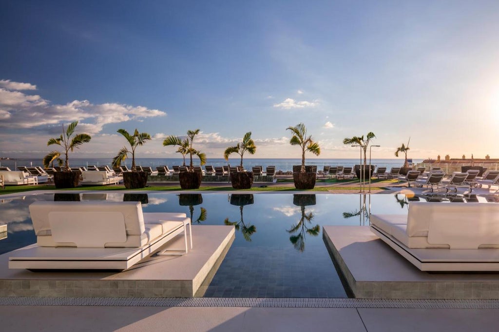 Modern oceanfront resort with curved white architecture, infinity pools, and private terraces overlooking the Atlantic in Costa Adeje, Tenerife