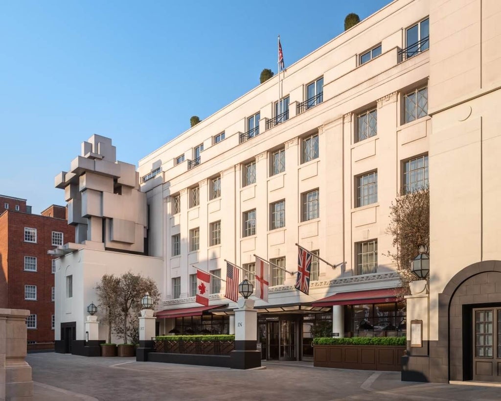 Opulent five-star hotel exterior in Mayfair with elegant stone facade, pristine white columns, and luxurious architectural details under soft evening light